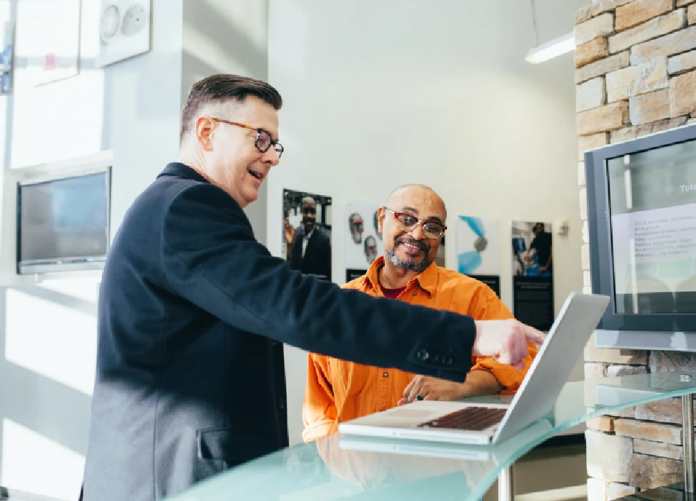 Two men are looking at a laptop computer.