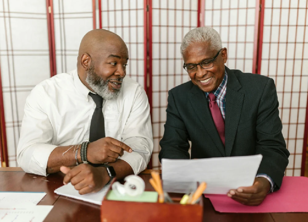 Two men sitting at a table looking at papers.