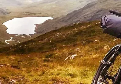 A person riding a bike on top of a grass covered hill.