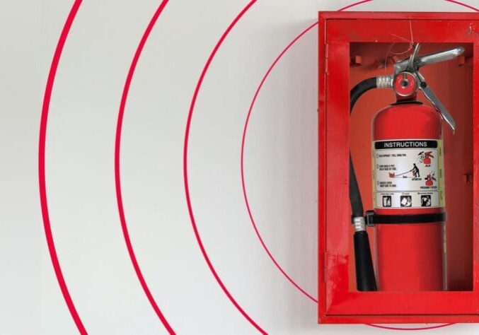 A red fire extinguisher in the middle of a wall.